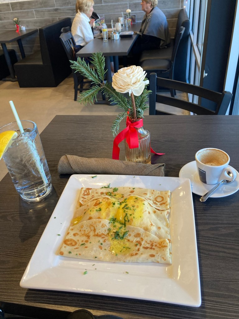 Crepe on a small table with a glass of water and an espresso