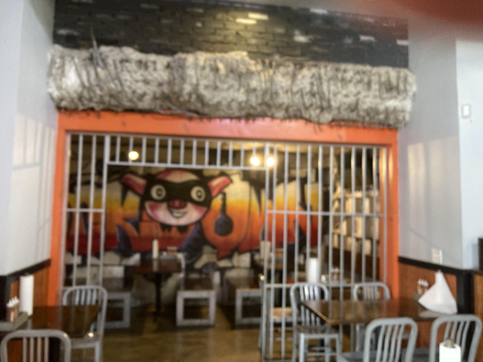 A mock jail cell is seen in this restaurant, on the back wall of which is a pig in a mask.